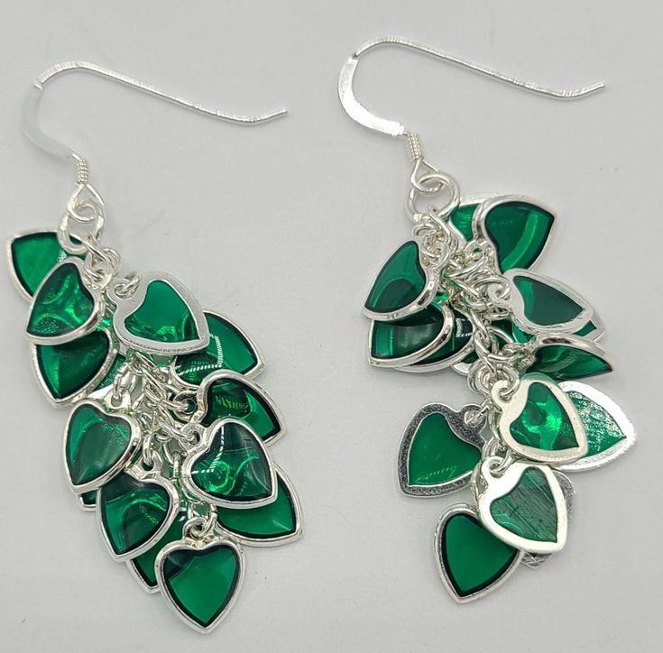 Earrings are made with a dangle that has 13 green hearts attached to a silver chain.  The dangle is 1 1/2 inches in length and 1/2 inch wide.   The total length of the earrings is 2 inches and each earring has a sterling silver earring wire Green Dangle Jewelry With Dangling Charms, Green Dangle Jewelry With Charms, Green Dangling Charms Jewelry, Green Heart-shaped Earrings For Valentine's Day, Green Heart Drop Earrings For Gifts, Green Nickel-free Heart Earrings As Gift, Green Nickel Free Dangle Chandelier Earrings, Green Heart Earrings For Valentine's Day Party, Green Nickel-free Dangle Chandelier Earrings