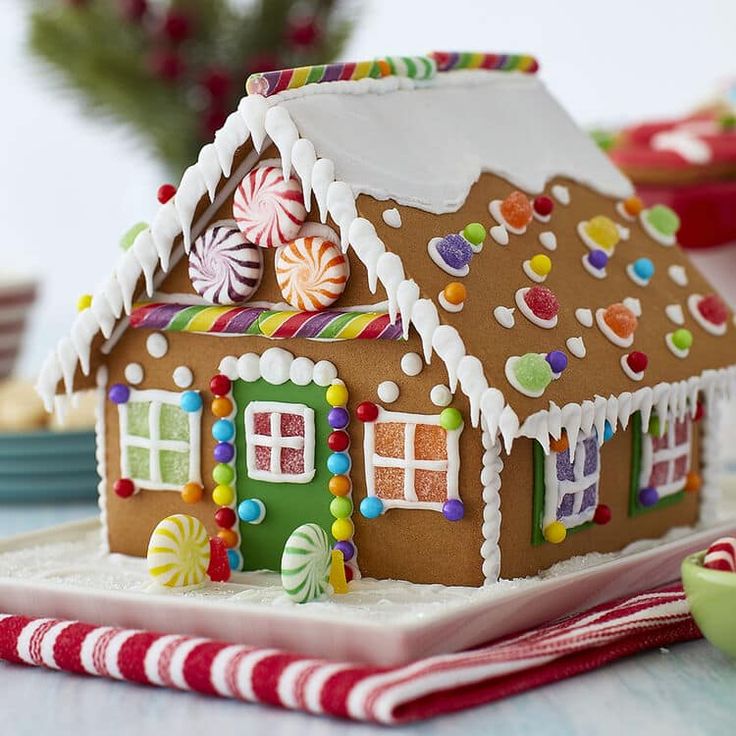 a gingerbread house decorated with candy canes and candies on a white plate