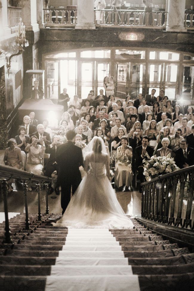 a bride and groom are walking down the stairs at their wedding ceremony in front of an audience