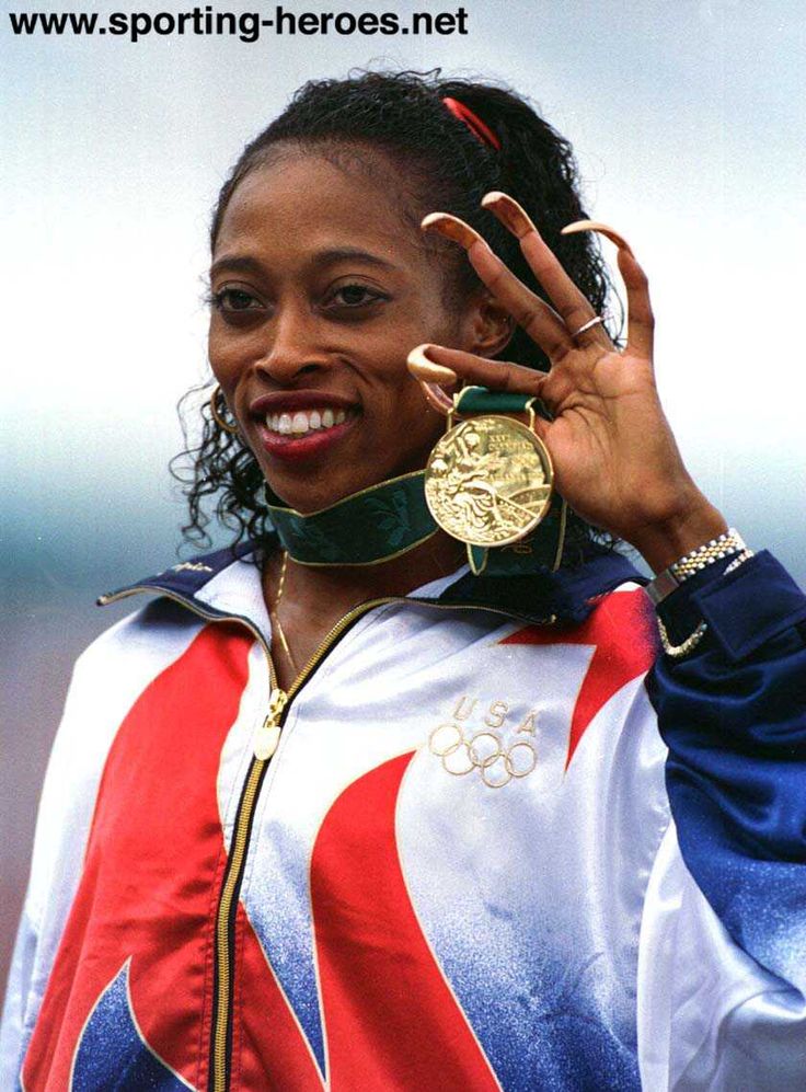 a woman with a gold medal on her left hand and wearing a blue, white, and red jacket