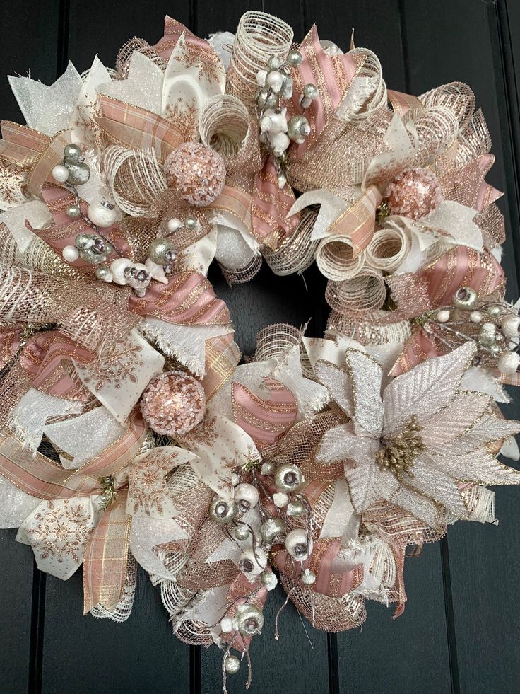 a pink and white wreath on a door with pearls, bows and other things around it