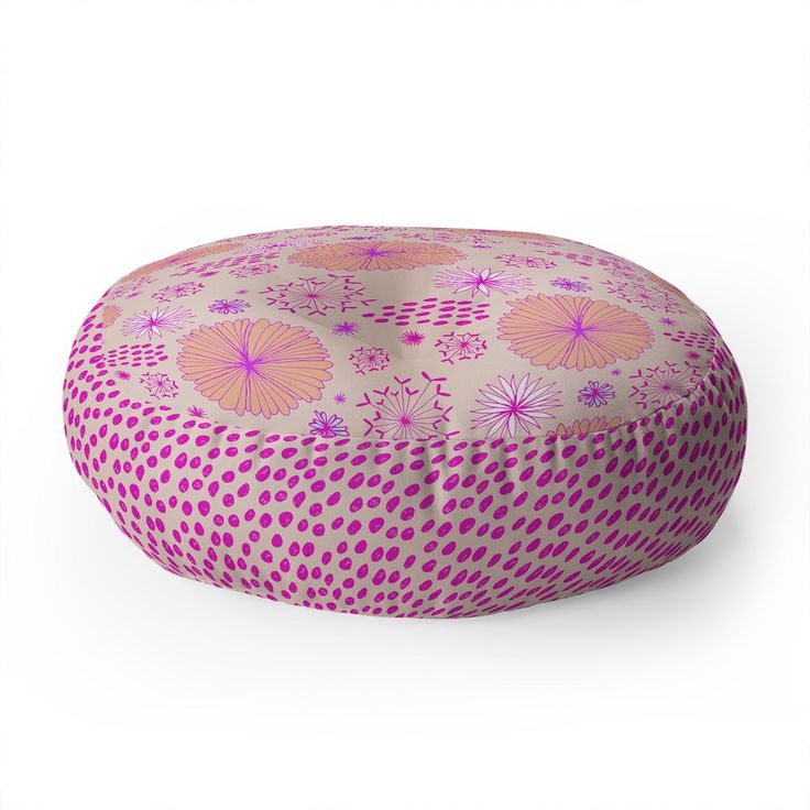 a round floor pillow with pink and purple designs on the front, sitting on top of a white surface