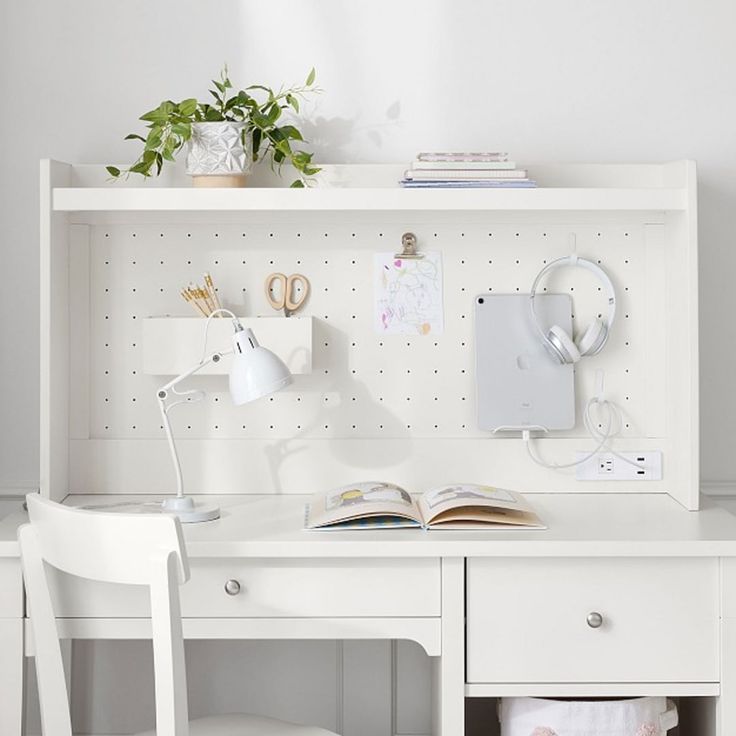 a white desk with two chairs and a book shelf above it that has an open book on top