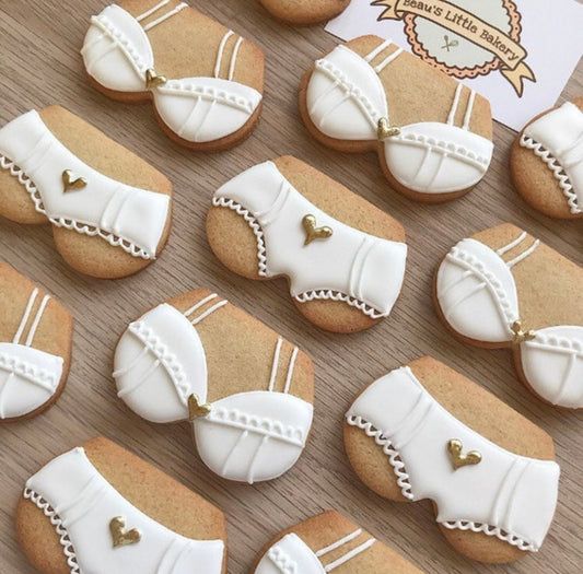 decorated cookies are arranged in rows on a wooden table with a card and price tag