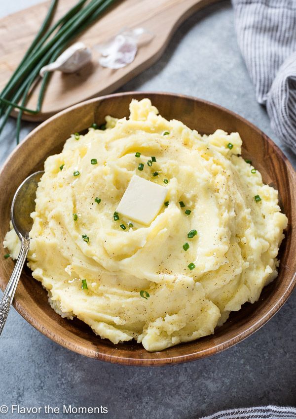 mashed potatoes with butter and parsley in a wooden bowl on a gray table