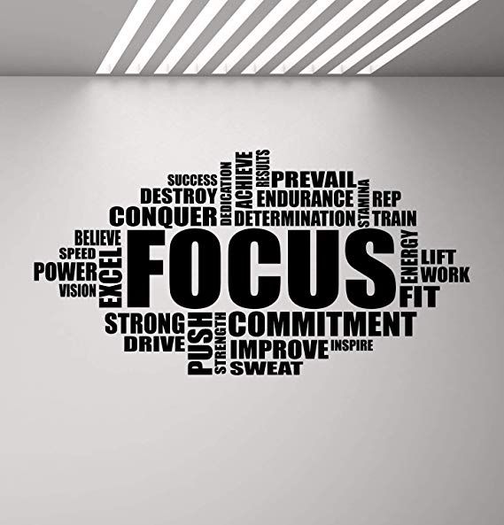 the word focus is written in black on a white wall above an office chair and desk