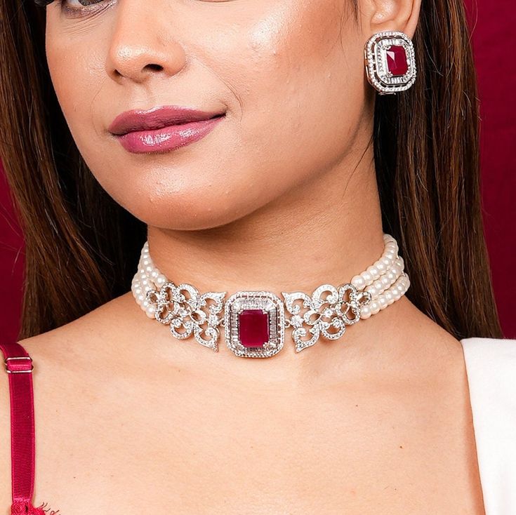 With this Manish Malhotra Jewelry Inspired, You can channel Princess Diana's iconic style with this Ruby Pearl Necklace. Wear a Ruby Choker Necklace to exude regality, or a Red Diamond Necklace to exude opulence. Choose a Pearl Diamond Choker for a touch of class. Inspired by Princess Diana's timeless style, these pieces combine the allure of rubies with the delicate beauty of pearls and diamonds, adding a touch of royal elegance to any ensemble. *𝐏𝐑𝐎𝐃𝐔𝐂𝐓 𝐃𝐄𝐓𝐀𝐈𝐋* * Material: Brass * Plating: White Rhodium Plated * Stone: AAA-quality CZ diamond & Ruby. *𝐃𝐈𝐌𝐄𝐍𝐒𝐈𝐎𝐍𝐒*  Necklace * Weight: 55 gm * Width: 1.15 Inches * Design Length: 10 inches * Total Length with Closure: 14.2 inches  Earrings * Weight: 9 gm each * Length: 1 Inch * Width:  0.9 Inches * Closure: Push Back *? Ruby Diamond Choker, Choker Diamond Necklace, Diamond Ruby Necklace, Red Ruby Necklace, Ruby Choker, Ruby Red Necklace, Modern Classic Wedding, Pearl Diamond Necklace, Choker Sets