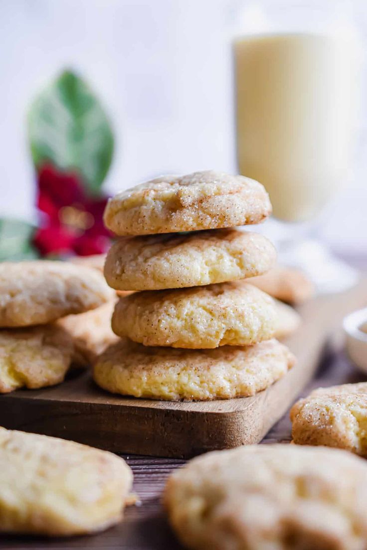 a stack of cookies sitting on top of a wooden cutting board next to a glass of milk