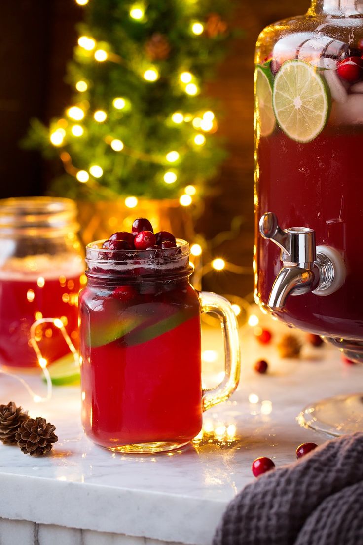 two mugs filled with red liquid next to a christmas tree