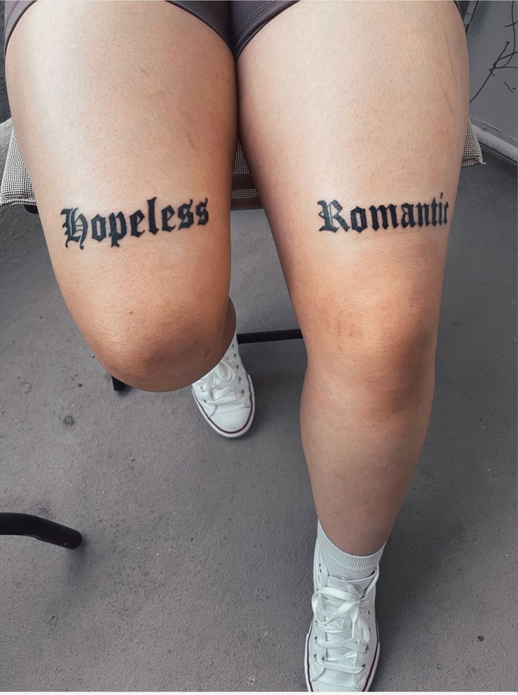 two people with small tattoos on their legs that say homeless and romani in cursive writing