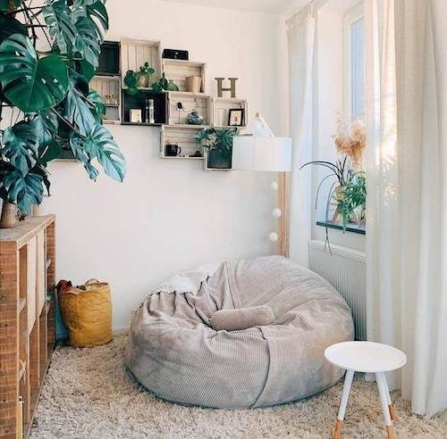 a living room with a large bean bag chair in the corner and plants on the wall