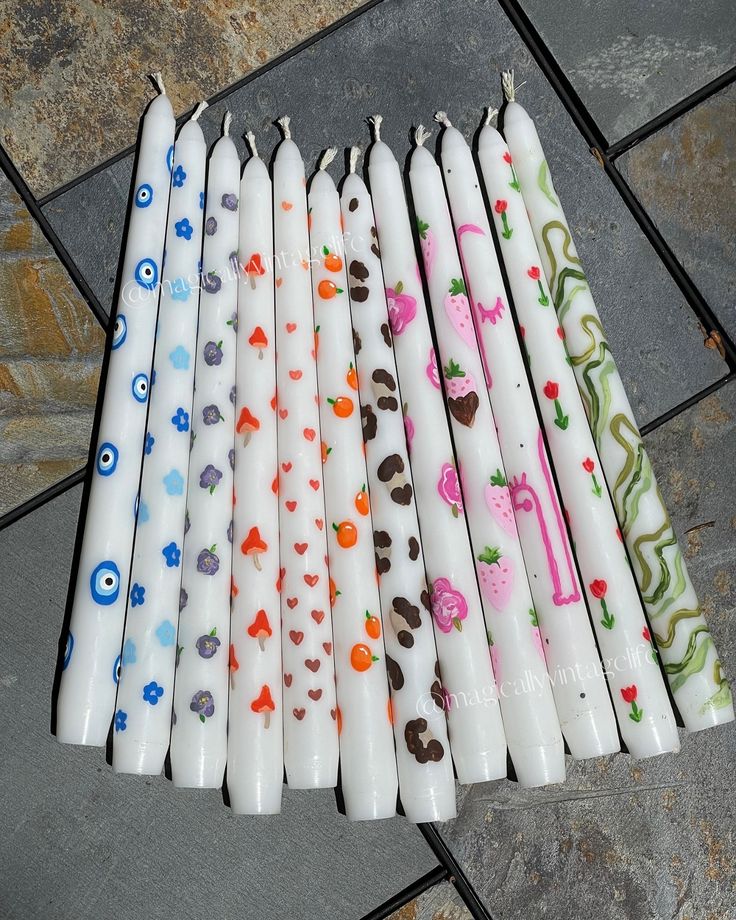 six candles with different designs on them sitting on a tile floor