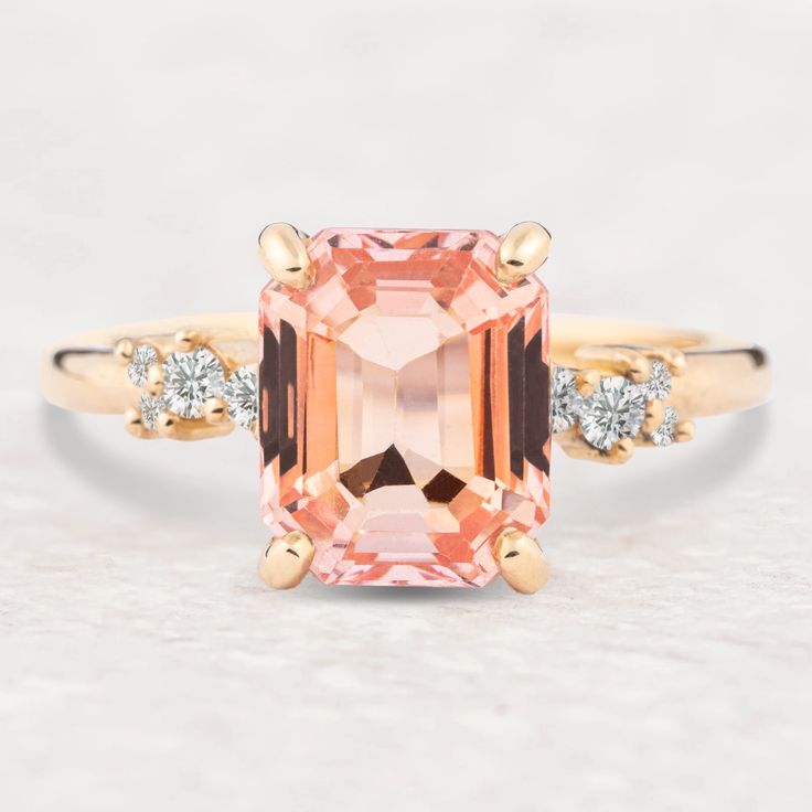 an orange and white diamond ring with two diamonds around it