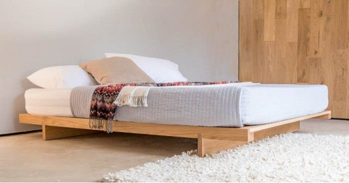 a bed sitting on top of a white rug next to a wooden headboard and foot board