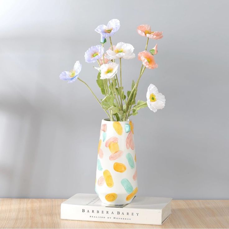 a vase with flowers sitting on top of a book