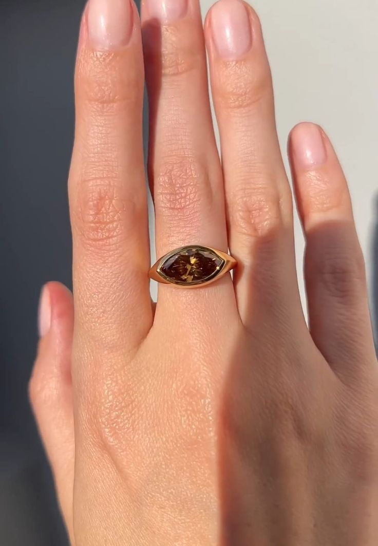 a woman's hand with a gold ring on it and a brown stone in the middle