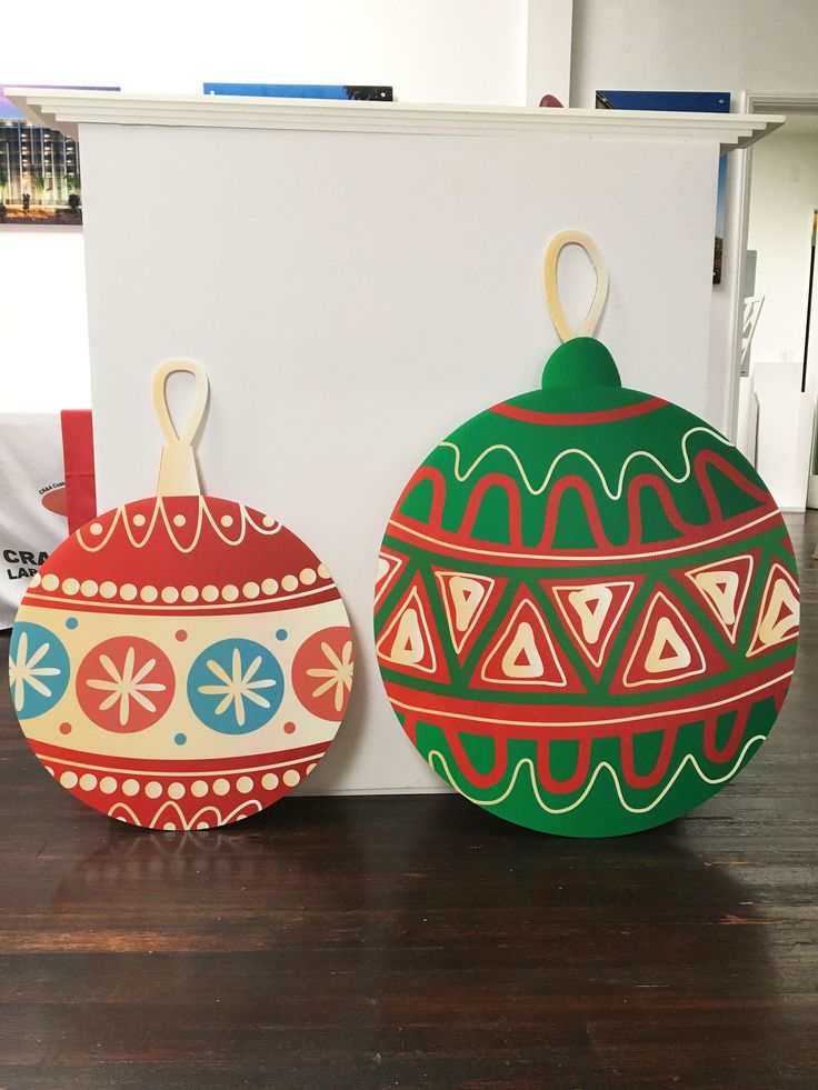 two decorative ornaments sitting on top of a wooden table next to a white box with a red and green ornament