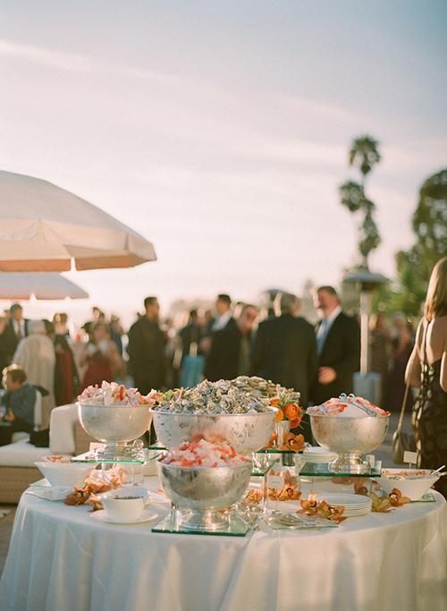 a group of people standing around a table with plates and bowls on top of it