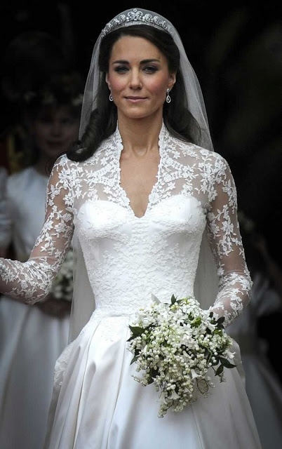 a woman in a wedding dress holding a bouquet and wearing a tiara on her head