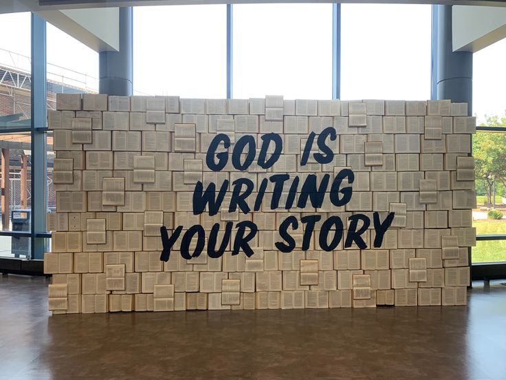 a sign that says god is writing your story on it in front of some windows