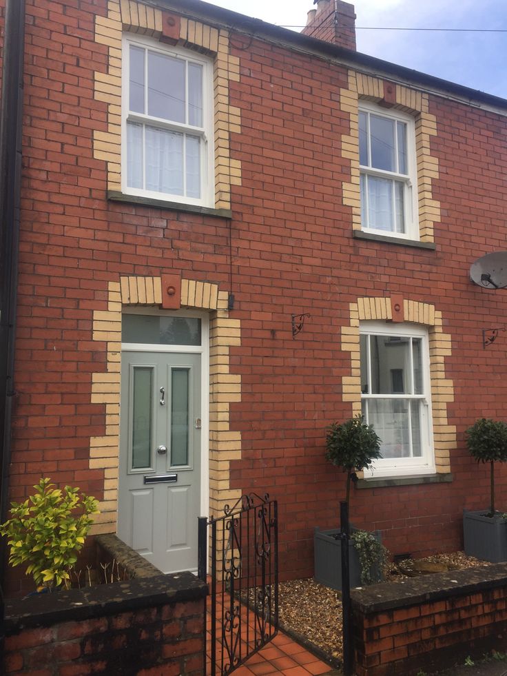 a red brick house with two windows and a gated in area next to it