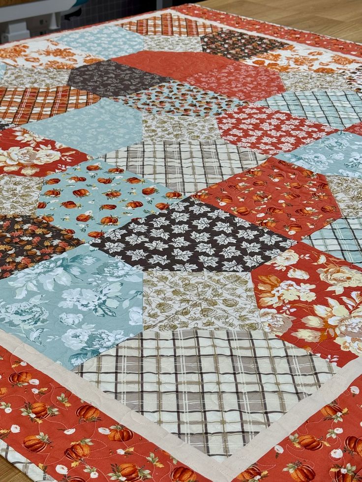 a patchwork table topper on a wooden table with an orange and white flowered design