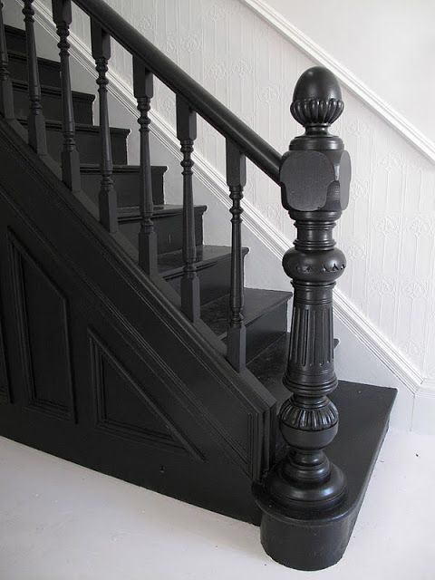 a cat is sitting on the stairs next to some black railing and handrails