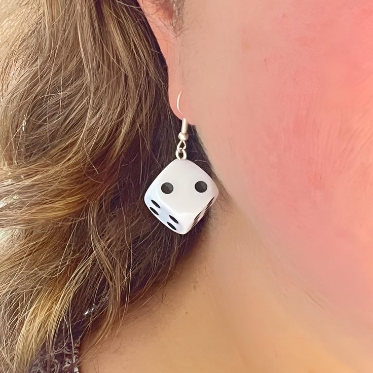 Perfect for gamers and fashion enthusiasts alike!  Our eye-catching Dangle Dice Earrings are crafted from standard-sized white dice, these earrings blend playful charm with a bold statement. Each earring features a single die, showcasing the classic dot design, adding a fun and quirky twist to your accessory collection. The dice drop length is 4 cm and they are securely attached to high-quality metal hooks, ensuring durability and comfort for all-day wear. Whether you're heading to a game night, a casual outing, or looking to add a personality to your everyday style, these earrings will turn heads and spark conversations. Add a roll of the dice to your look with our Dangle Dice Earrings - where fashion meets fun! Card Game Earrings, White Novelty Dangle Jewelry, Novelty White Dangle Jewelry, Novelty White Hypoallergenic Jewelry, Hypoallergenic White Novelty Jewelry, Novelty Hypoallergenic White Jewelry, Hypoallergenic Novelty White Jewelry, Novelty White Pierced Jewelry, Adjustable Novelty Single Earring Jewelry