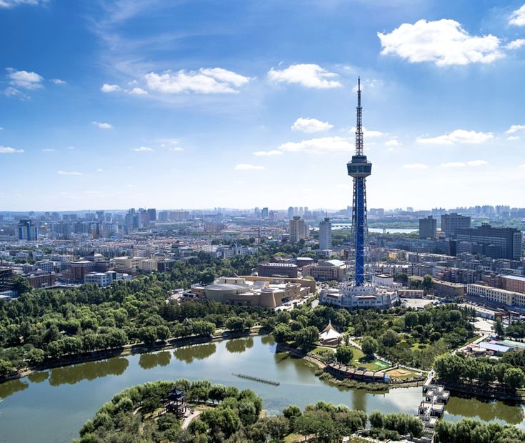 an aerial view of a city with a lake in the foreground and a tall tower in the background