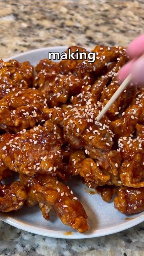 someone is holding a skewer over some food on a plate with sesame seeds