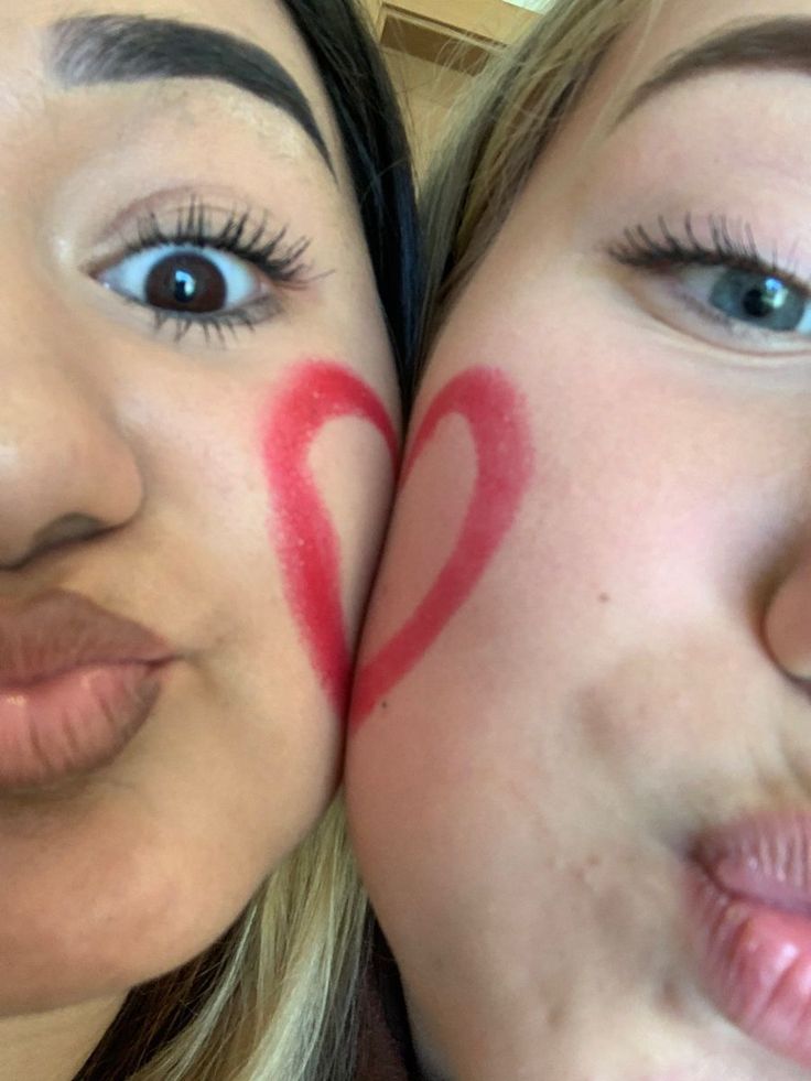 two women with painted hearts on their faces