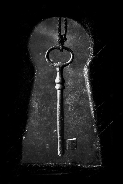 an old key with a chain hanging from it's center, in the dark