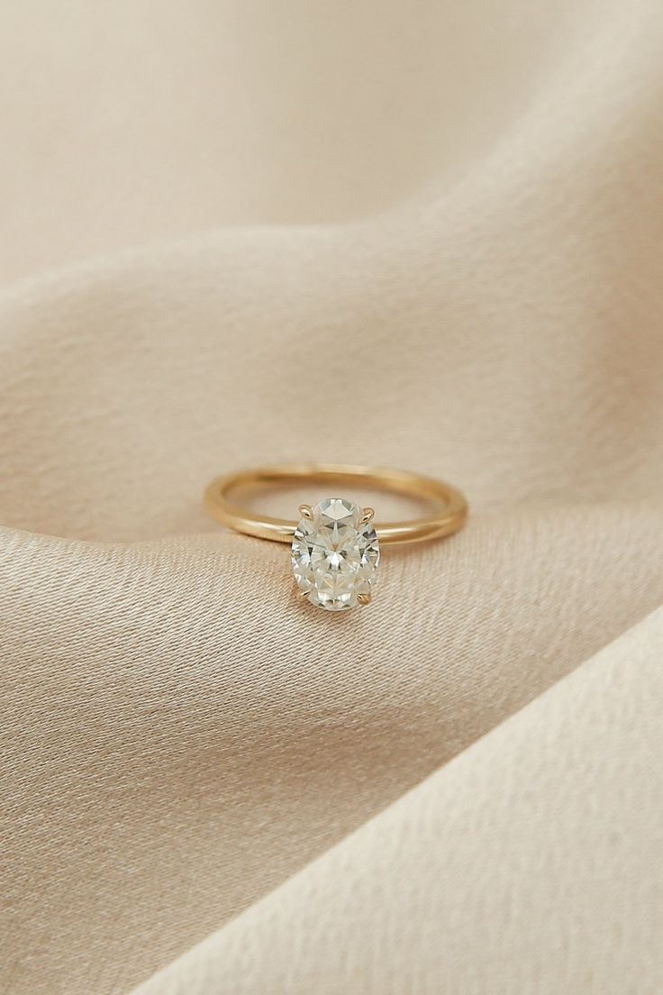 an engagement ring with a single diamond on top of a white cloth covered surface,