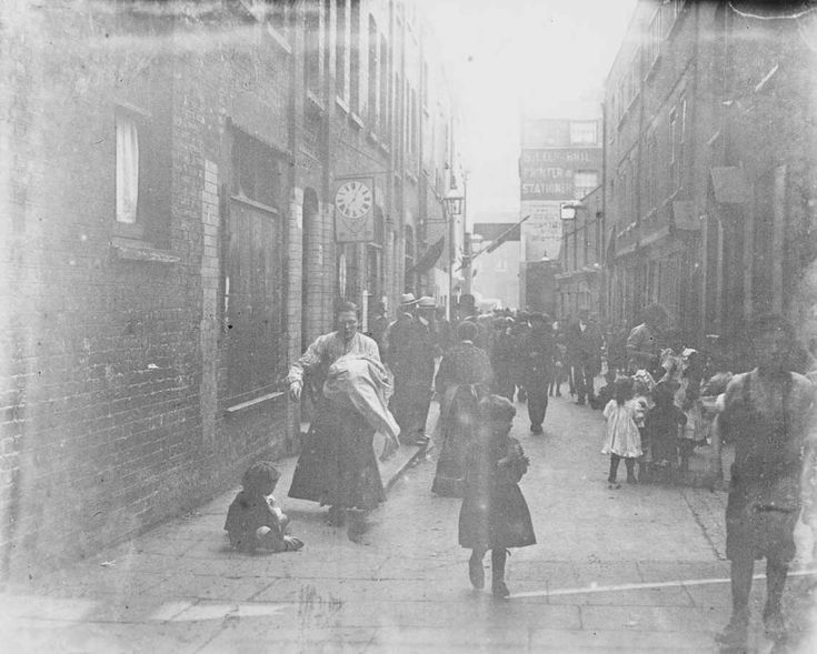 an old black and white photo of people walking down the street