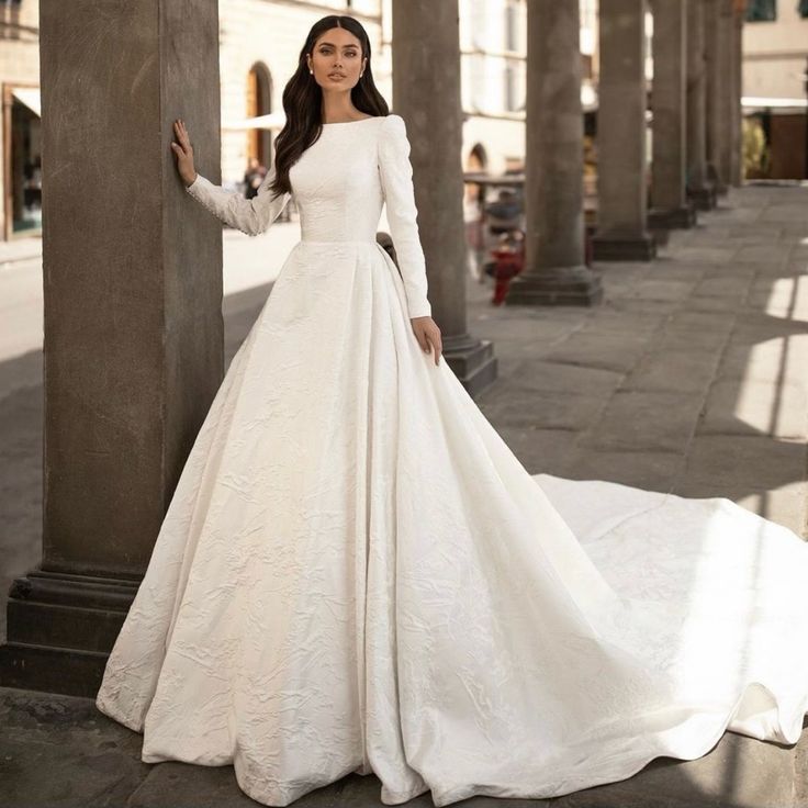 a woman in a white wedding dress standing next to columns