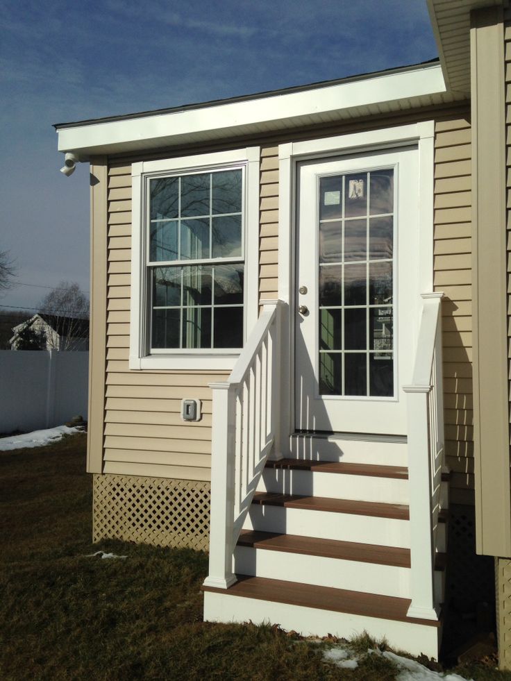 a small house with steps leading up to the front door and side porch on a sunny day