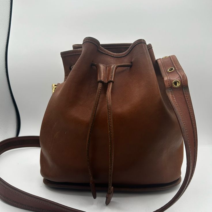 British Tan Vintage Coach Bucket Bag In Fair Condition, A Couple Discolored Sections Pictured In Pictures 3&4 Classic Bucket Shoulder Bag With Gold-tone Hardware, Classic Satchel With Dust Bag For Errands, Brown Bags With Gold-tone Hardware In Bucket Shape, Elegant Bucket Bag With Brass Hardware For Daily Use, Classic Bucket Satchel With Removable Pouch, Formal Bucket Bag With Brass Hardware, Travel Bucket Bag With Brass Hardware, Elegant Bucket Shoulder Bag With Brass Hardware, Classic Formal Brown Bucket Bag