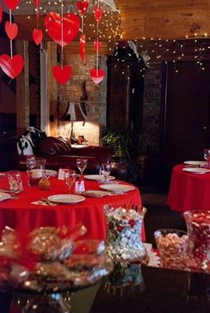 a room filled with lots of tables covered in red cloths and hearts hanging from the ceiling