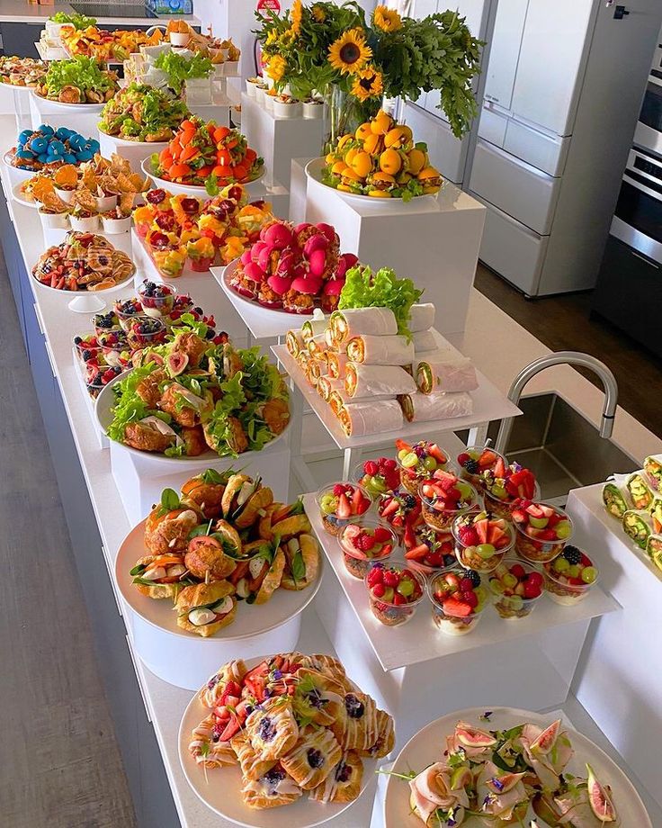 a buffet table filled with lots of different types of food on plates and trays