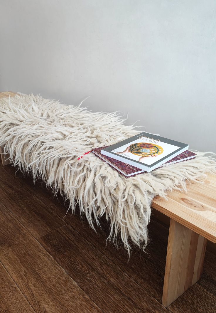 a white furry bench with a book on it's back and wood flooring