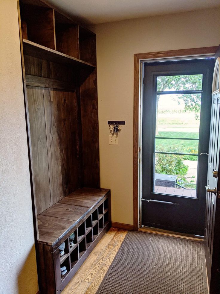 an empty entryway with a wooden bench next to the door and open bookcase