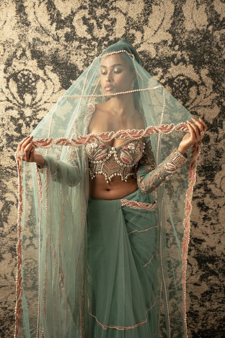 This enchanting dusty turquoise saree is crafted from delicate net fabric, radiating an ethereal charm that captivates the imagination. Paired with a matching net blouse adorned with a flair of pink, it emanates a bridal and festive aura that is simply irresistible. So mesmerizing is its allure that one might be compelled to invent an occasion just to don its elegance and grace. Perfect for weddings, celebrations, or any special event, this saree is a true embodiment of beauty and festivity, des Turquoise Saree, Placement Pattern, Cutdana Embroidery, Green Drapes, Net Blouse, Net Embroidery, Saree And Blouse, Net Blouses, Simply Irresistible