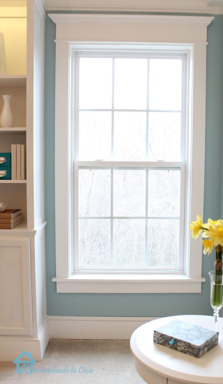 a living room with blue walls and a white coffee table in front of a window