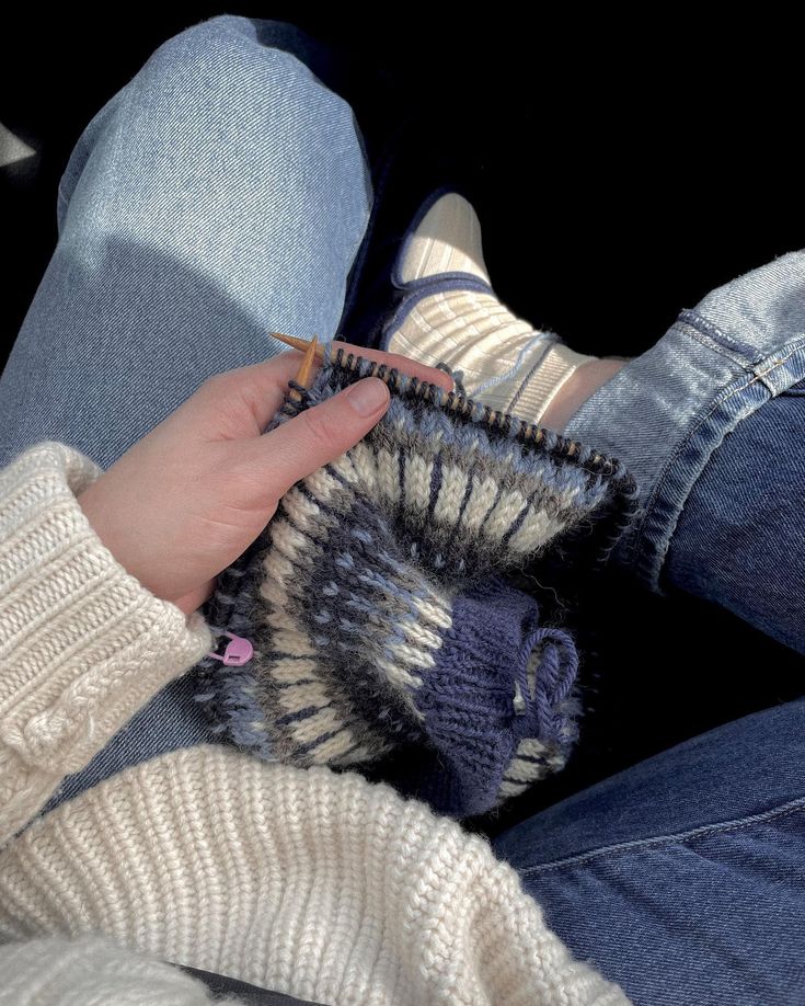 a person is holding a knitted object in their lap and knitting it to someone's leg