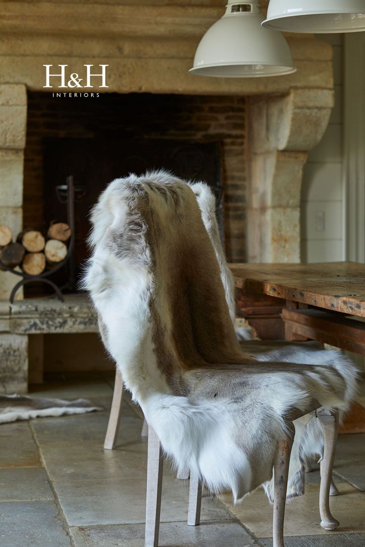 a chair with fur on it in front of a fire place and fireplace mantel