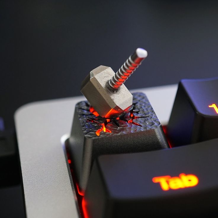 a close up of a computer keyboard with a hammer stuck in it