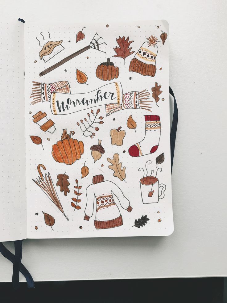 an open notebook with autumn doodles on the cover and writing in black marker pen