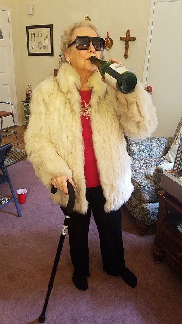 an older woman in a fur coat drinking from a wine bottle