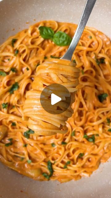 a bowl filled with pasta and garnished with parsley on the side, being held by a fork