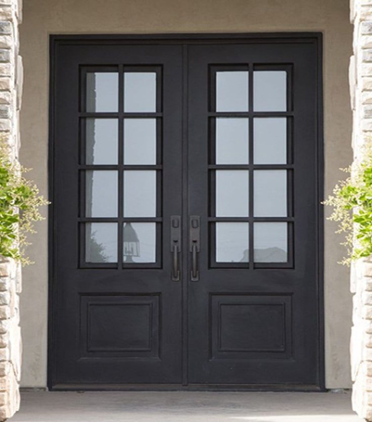 a black double door with two sidelights and brick pillars on the front of a house